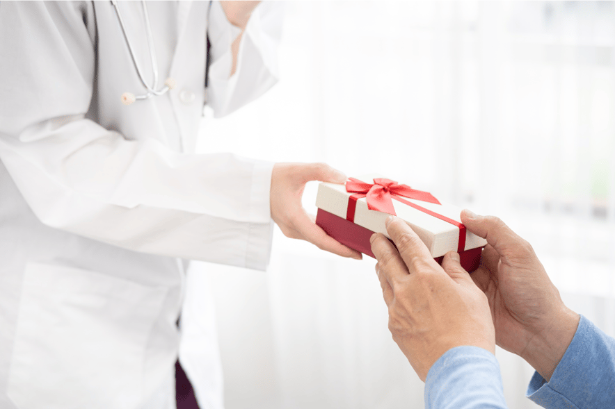 Patient handing a small wrapped gift with a red ribbon to a doctor, symbolizing modest gratitude in healthcare.