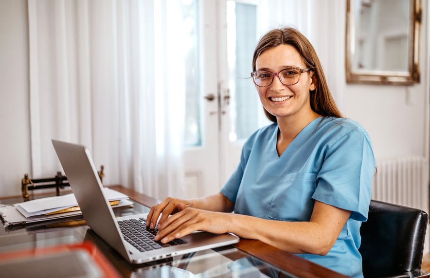 Medizinische Fachkraft arbeitet am Laptop zur Verwaltung von Online-Patienteninteraktionen.