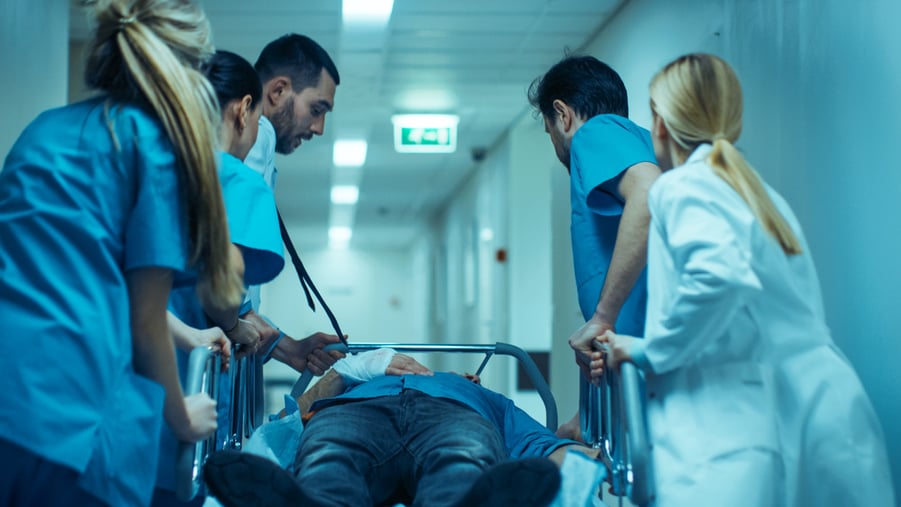 Emergency Department: Doctors, Nurses and Surgeons Move Seriously Injured Patient Lying on a Stretcher Through Hospital Corridors.