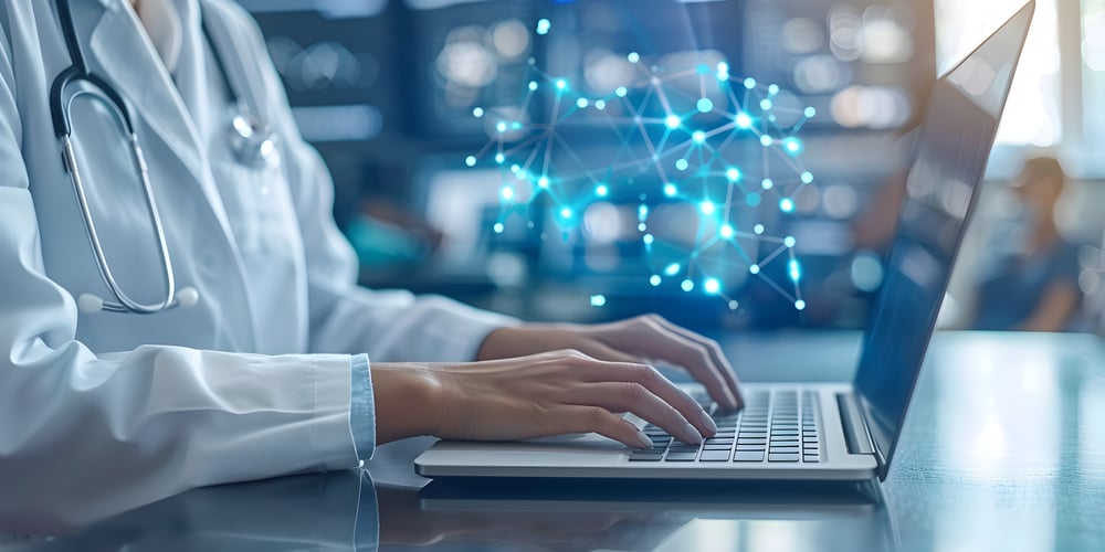 Hands of a doctor, wearing a white coat and a stethoscope, typing on a laptop.