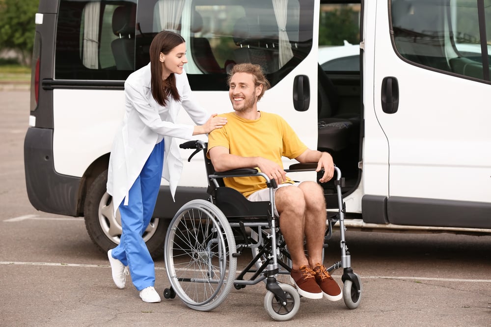 a patient transport assistant helping a young man in a wheelchair