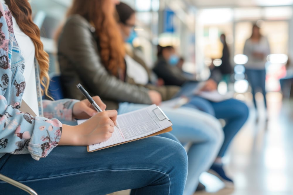 Patienten, die in einem Wartebereich mit unscharfem Hintergrund Formulare ausfüllen